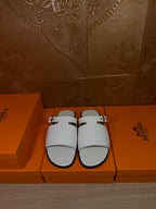 White slide sandals with two buckled straps and open toe, flat sole