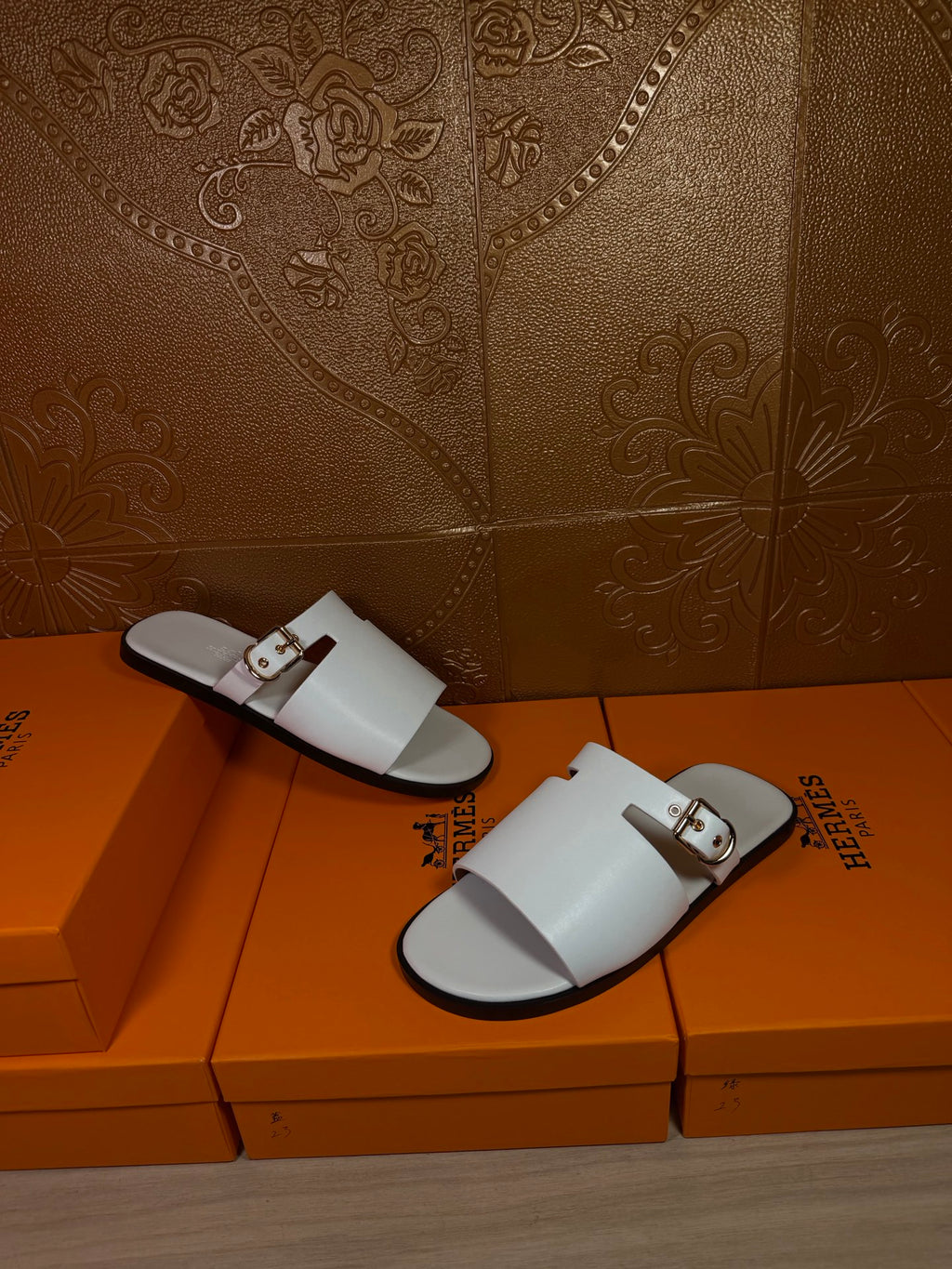 White slide sandals with open toe, double straps, and metal buckle accents