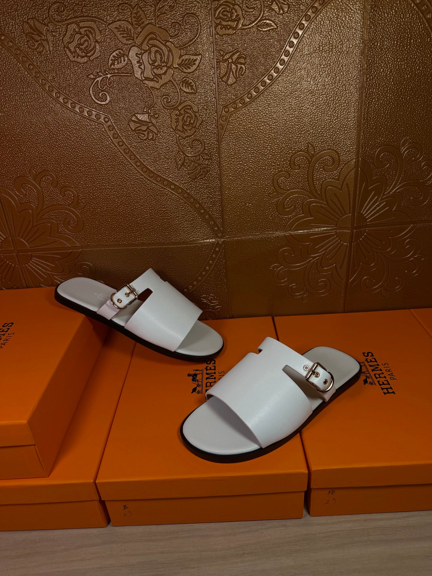 White slide sandals with open toe, double straps, and metal buckle accents