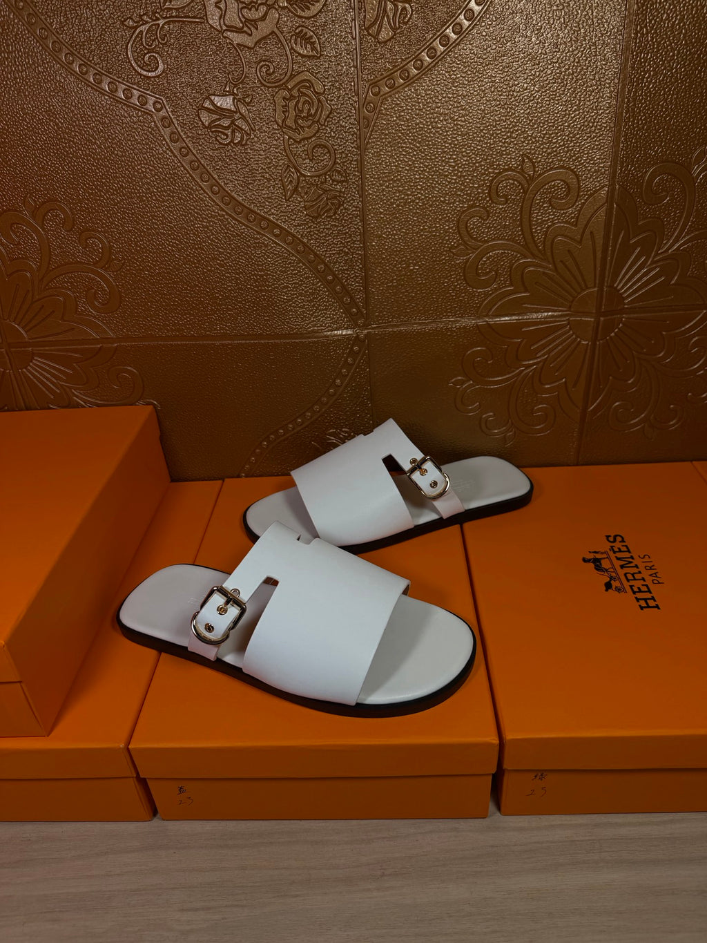 White slide sandals with double straps and metal buckle details, flat sole