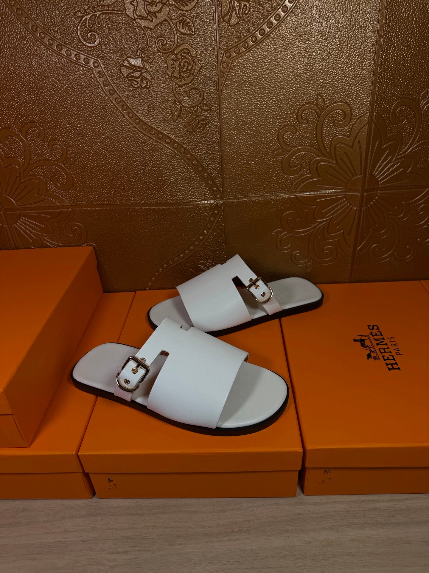 White slide sandals with double straps and metal buckle details, flat sole