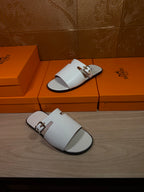 White slide sandals on display with open toe, double straps, and metal buckles