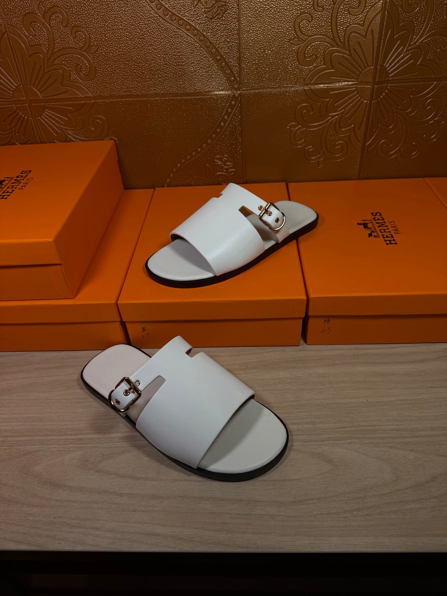 White slide sandals on display with open toe, double straps, and metal buckles