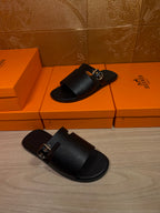 Black leather slide sandals with silver buckle and wide strap, two-shoe view