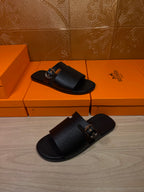 Black leather slide sandals with wide strap and silver buckle, top and bottom shoes