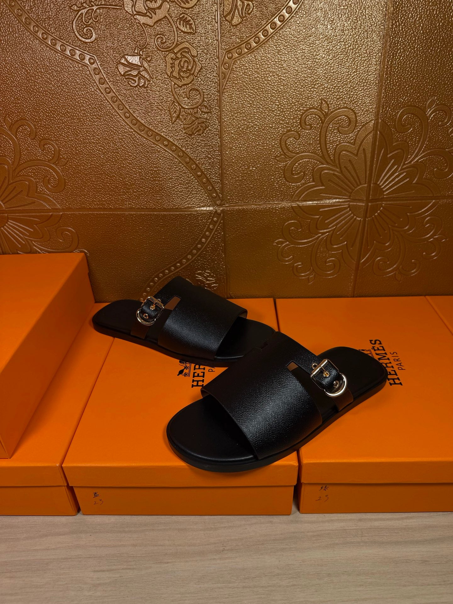 Black leather slide sandals with wide buckled strap, front 3/4 view