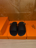 Black leather slide sandals with wide strap and silver-tone buckle