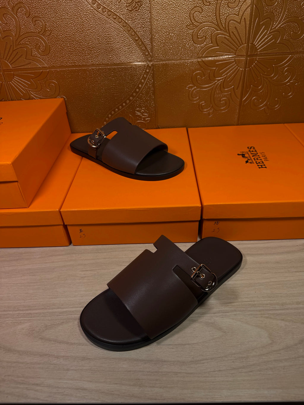 Pair of Hermes dark leather slide sandals with metal buckle on strap
