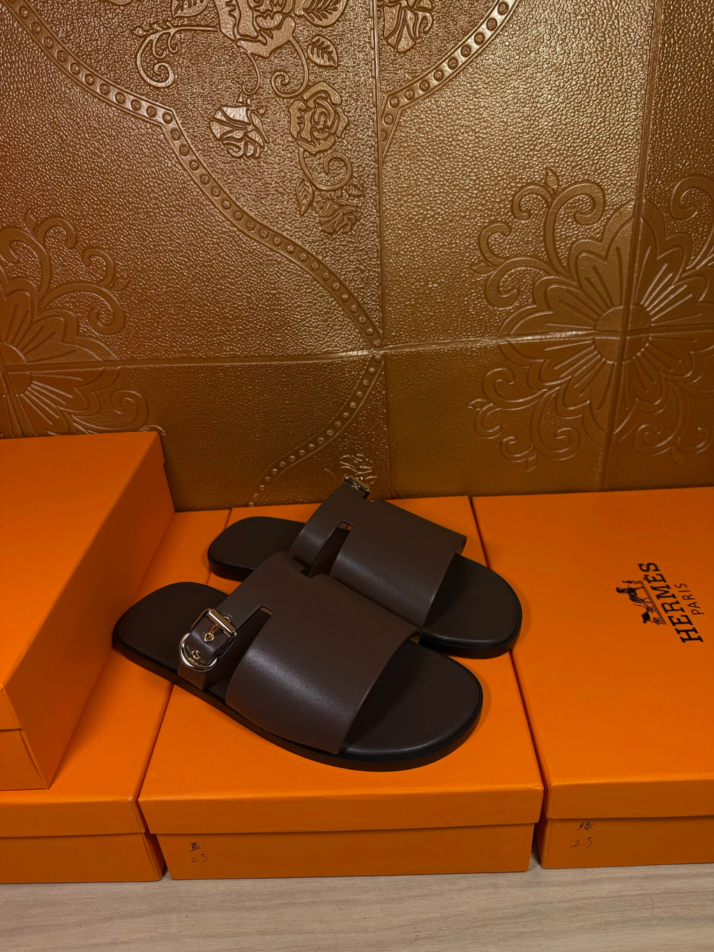 Hermes dark leather slide sandals with single buckle strap across foot