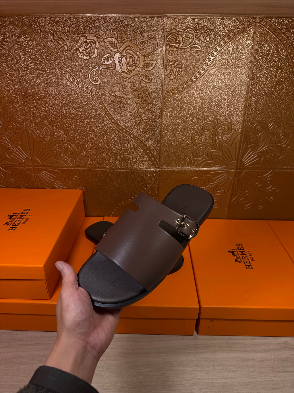 Hermes dark leather slide sandal held up, open toe with buckle strap