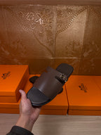Hermes dark leather slide sandal held up, open toe with buckle strap