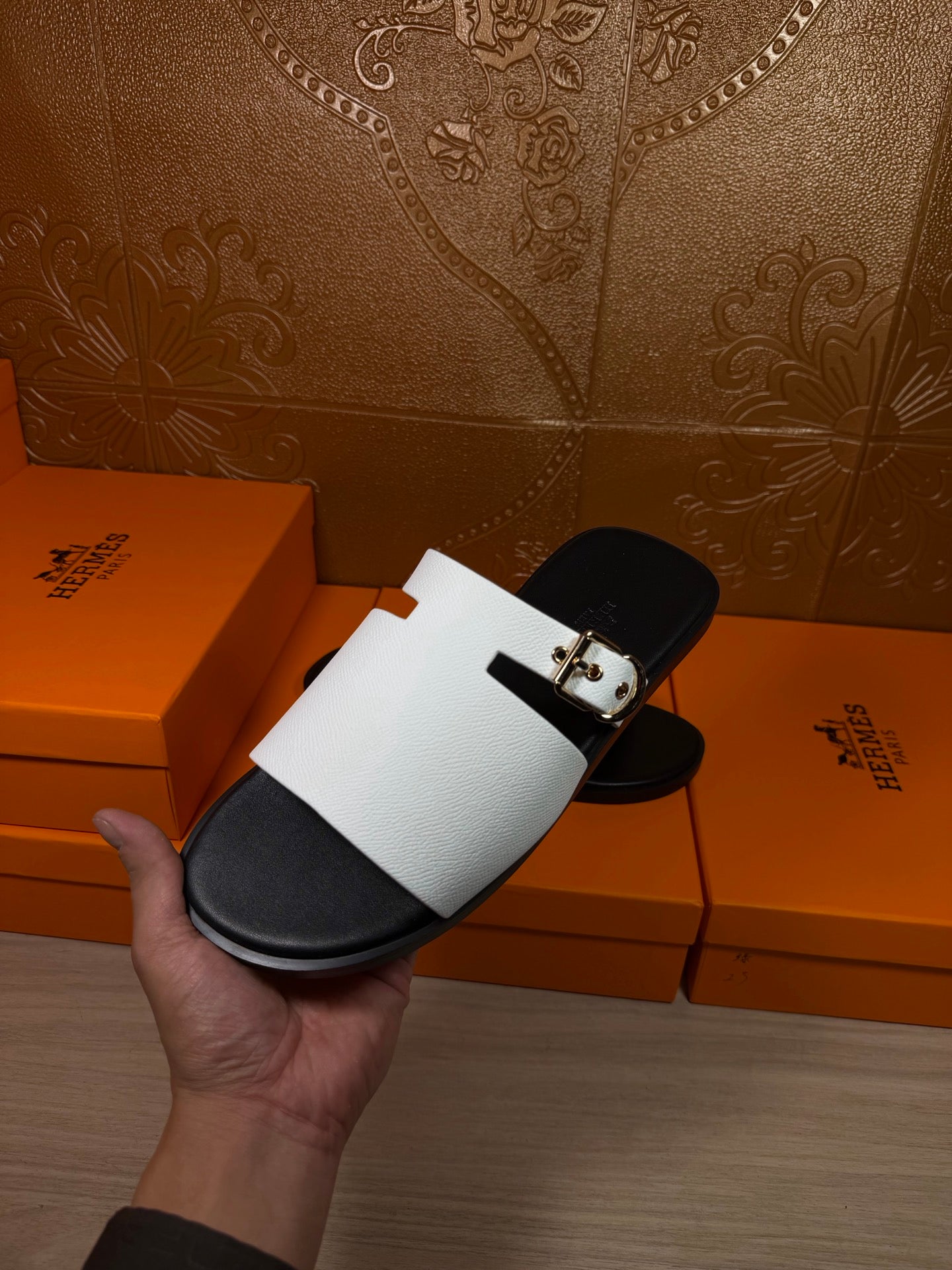 Hermes sandals held up: white strap with silver buckle and black sole footbed
