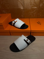 Hermes sandals with white straps and black footbeds, one sandal angled on box