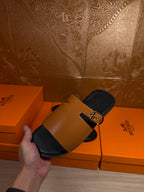 Leather slide sandal with tan strap and gold buckle, black footbed