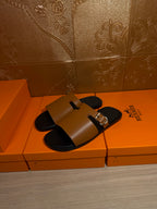 Leather slide sandals with tan uppers and gold buckles, black footbeds