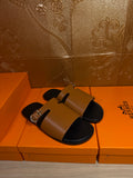 Hermes leather slide sandals with tan straps and gold buckle detail, black footbeds