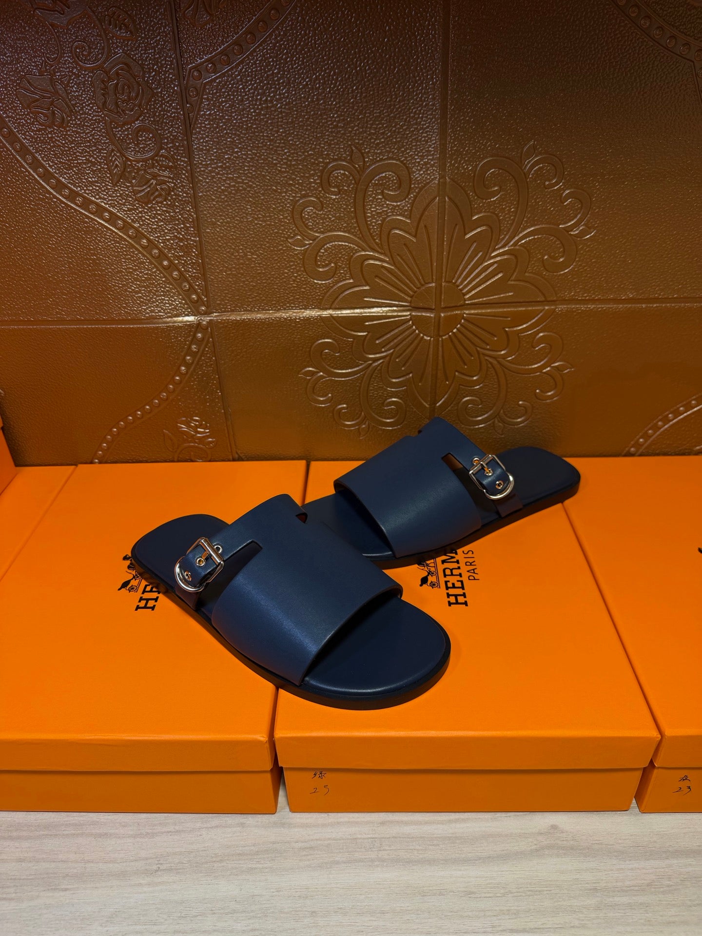 Hermes slide sandals, dark blue leather with adjustable double strap and gold buckles.