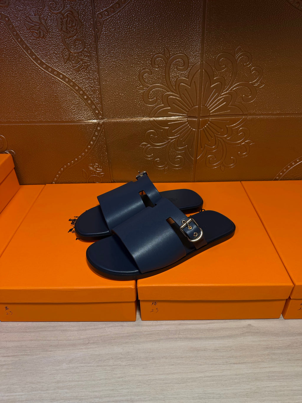 Hermes slide sandals, dark blue upper with front strap and gold square buckle.