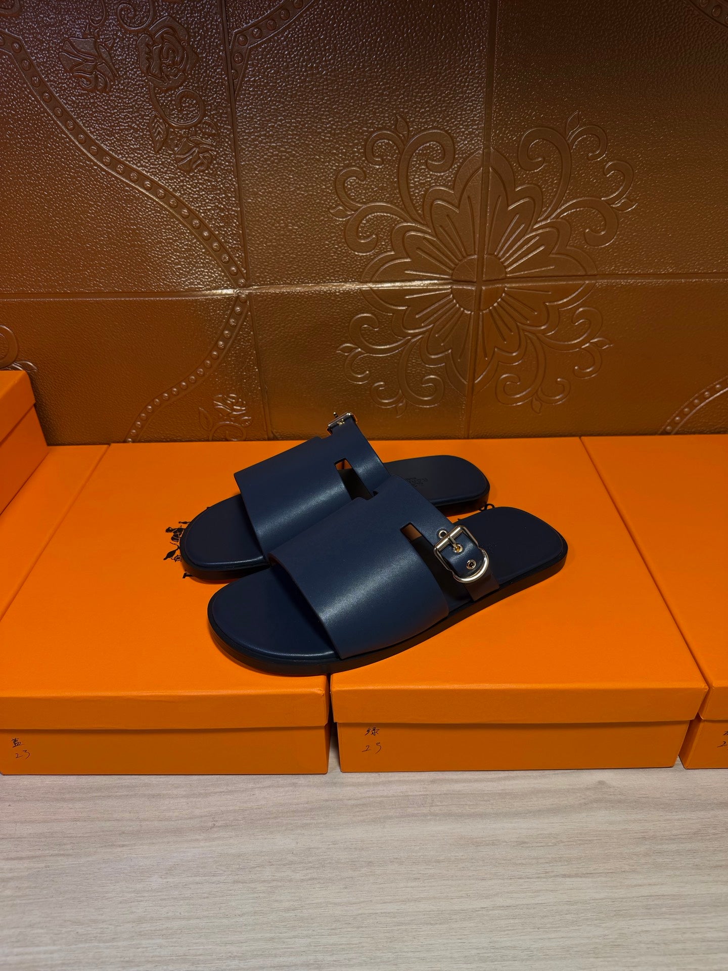 Hermes slide sandals, dark blue upper with front strap and gold square buckle.