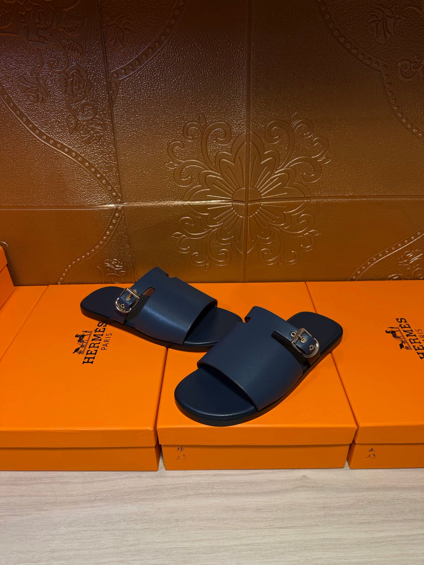 Hermes sandals, dark blue double-strap slides with gold buckle details and side logo.