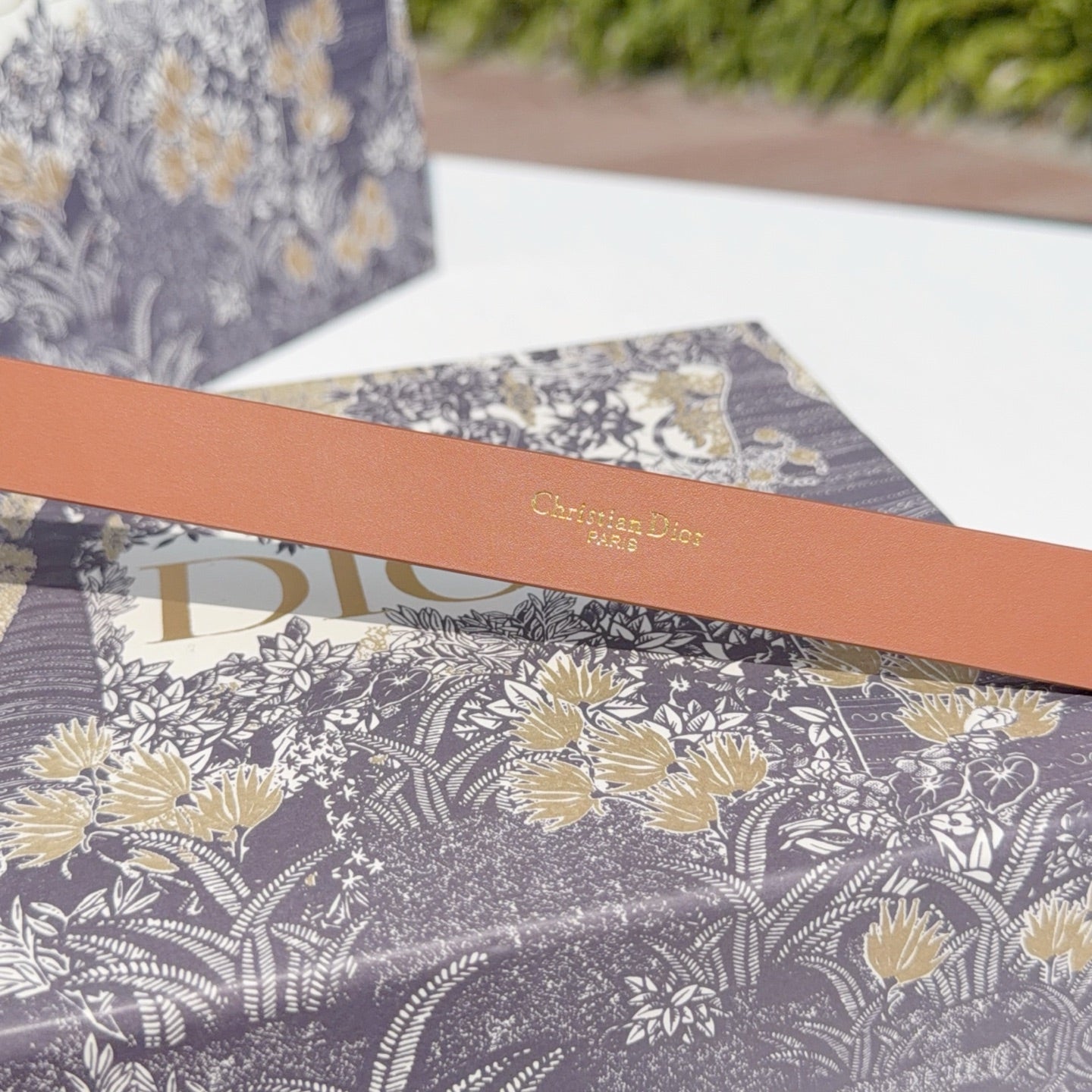Tan leather belt with 'Christian Dior' text stamp