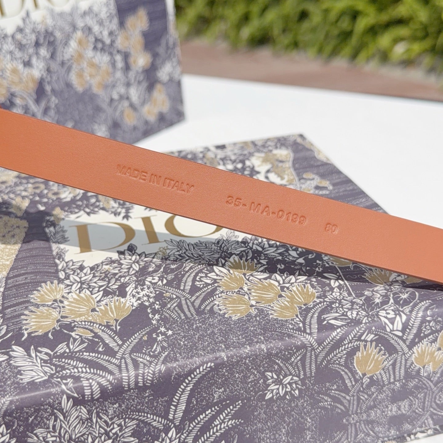 Tan leather belt with 'MADE IN ITALY' stamp and model code