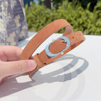 Dior belt buckle close-up with tan leather strap and silver oval clasp