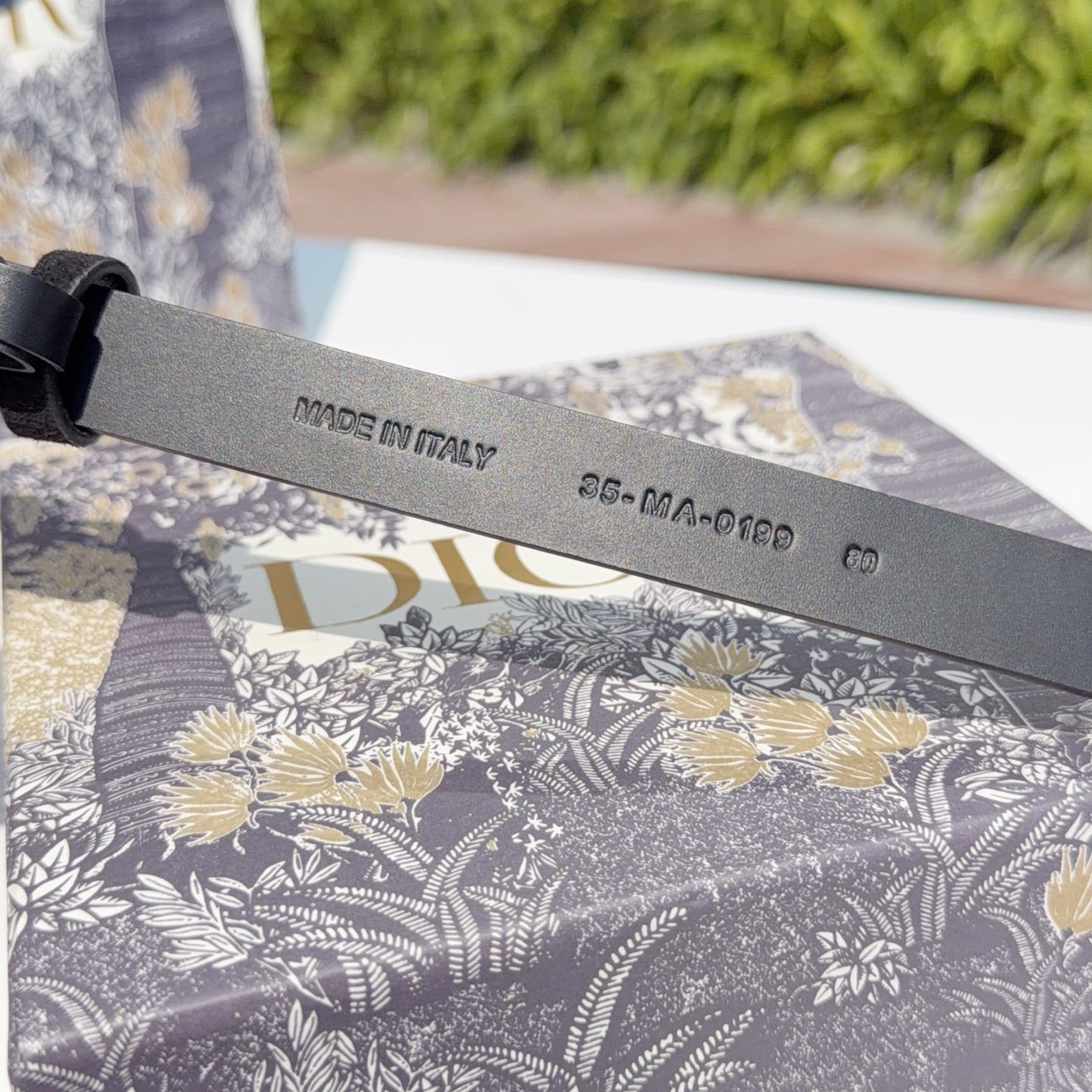 Dark leather belt with 'MADE IN ITALY' and code-stamped underside