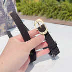 Dark leather belt with gold buckle clasp, held by hand
