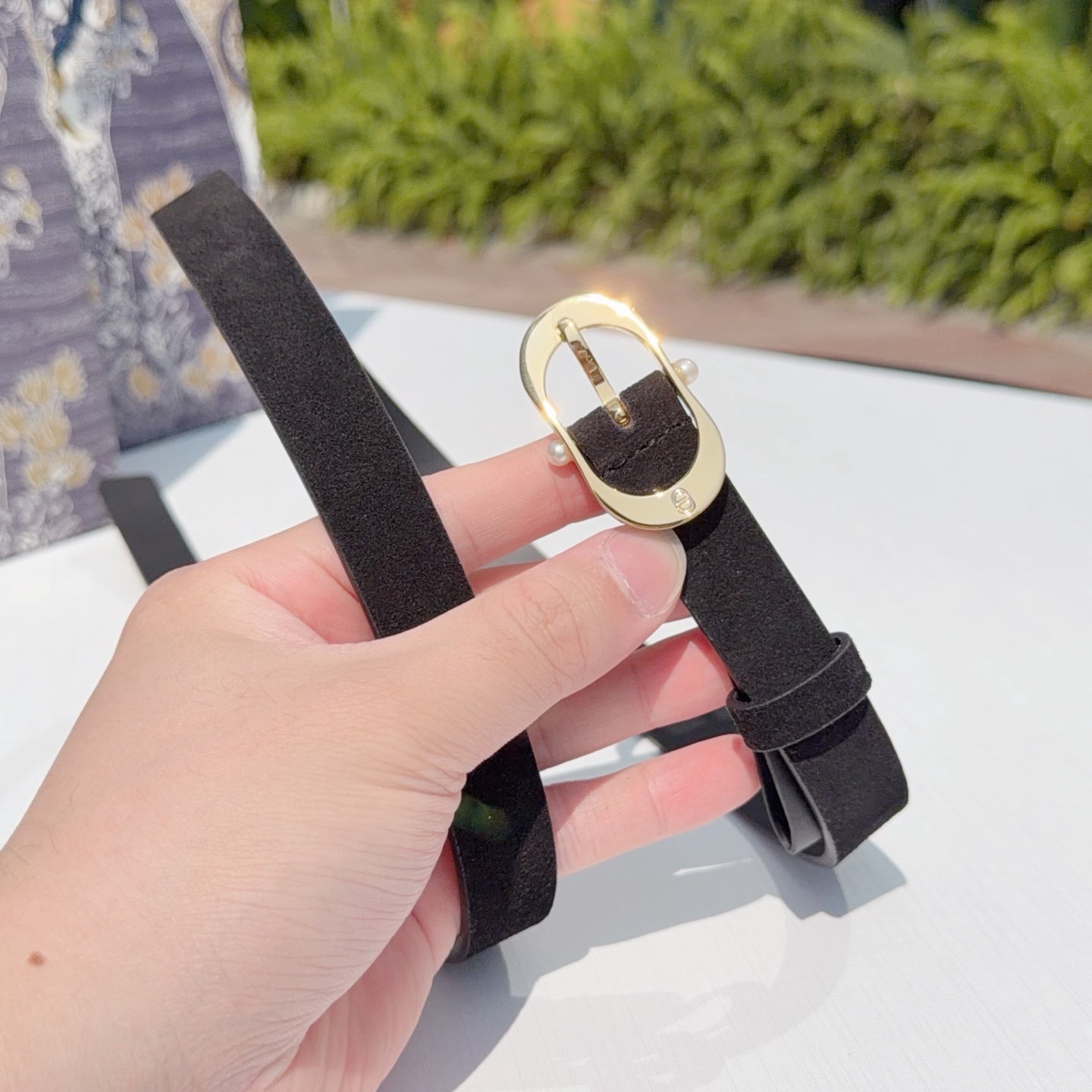 Dark leather belt with gold buckle clasp, held by hand