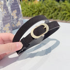 Dark leather belt held close-up, showing gold oval buckle
