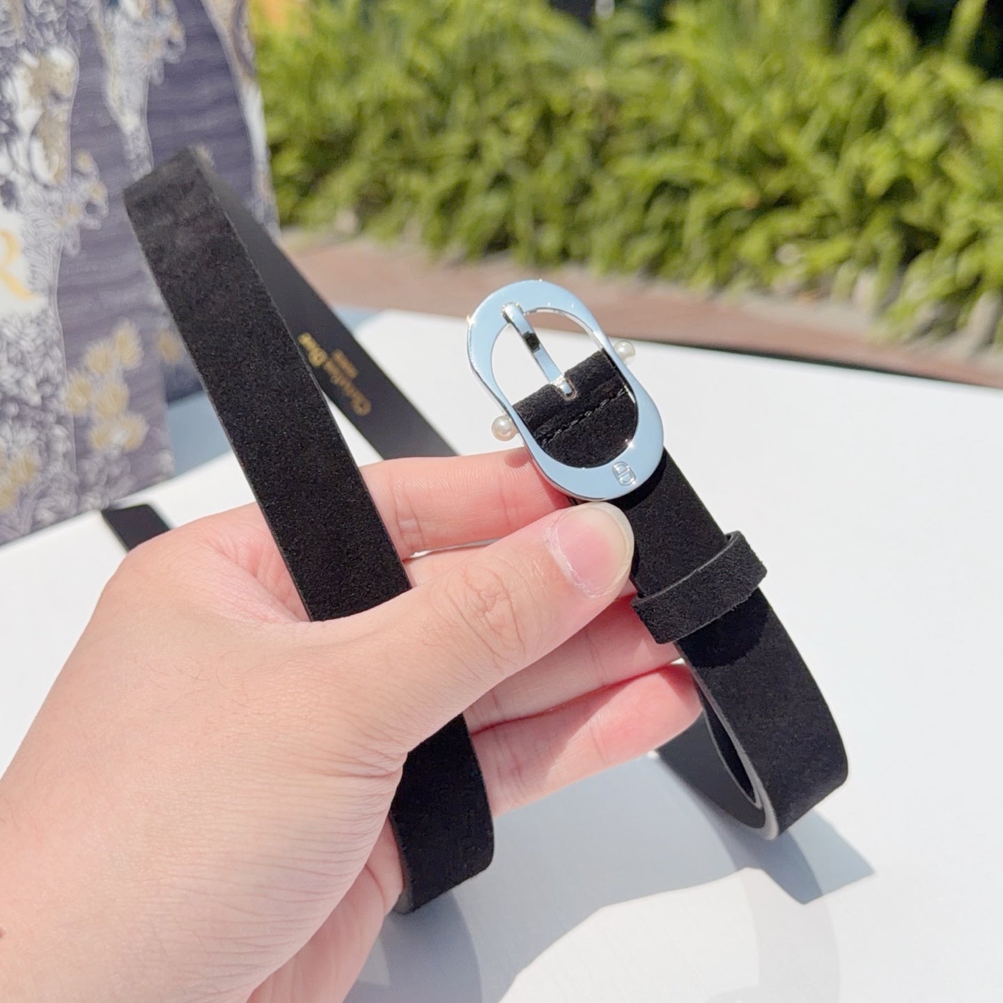Dior belt with dark strap and silver oval buckle, shown from side