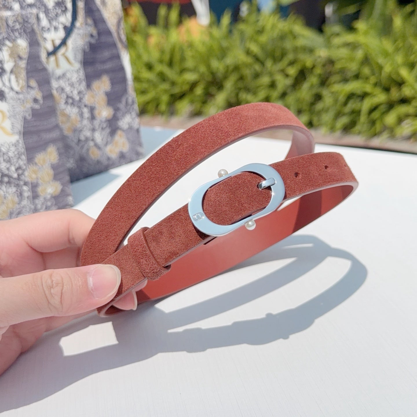 Reddish-brown leather belt with silver buckle detail and adjustable holes