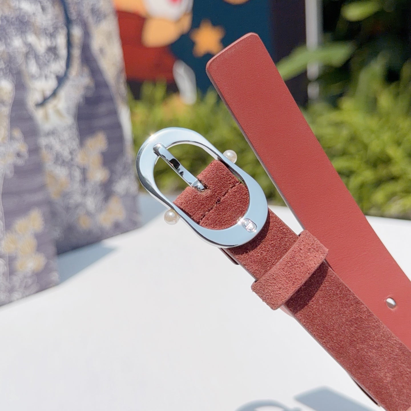 Reddish-brown leather belt with round silver buckle and metal keeper