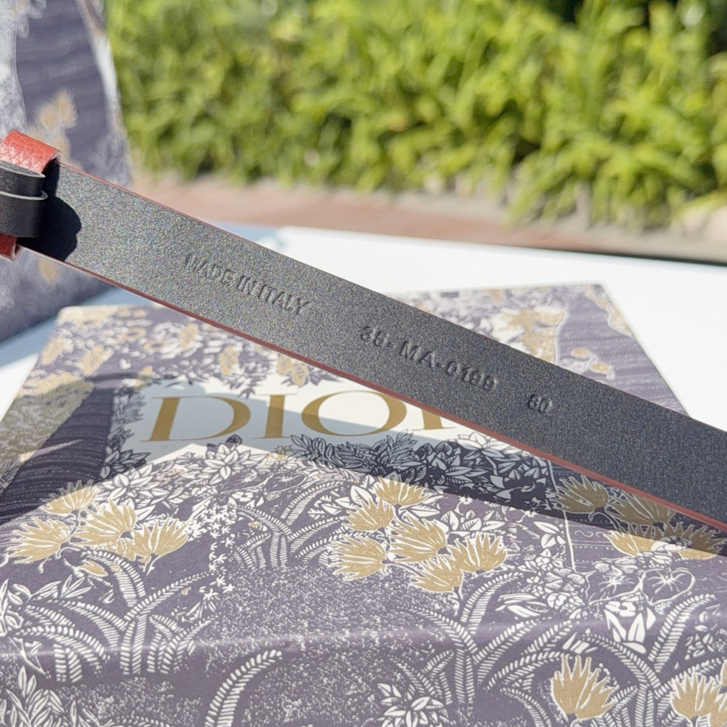 Grey leather belt underside with stamped text including 'Christian Dior' and numbers