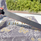 Grey leather belt underside with stamped text including 'Christian Dior' and numbers