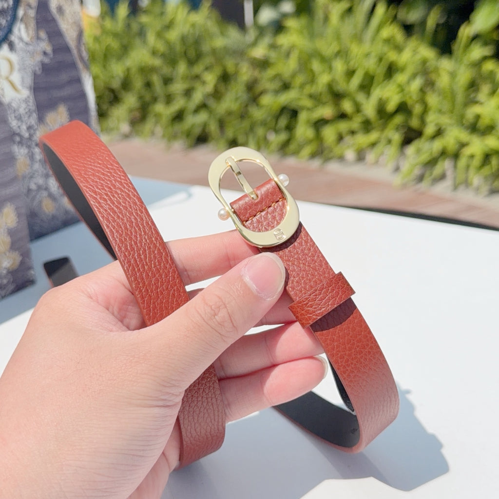 Coral leather belt with gold-tone double-ring buckle clasp, held by hand