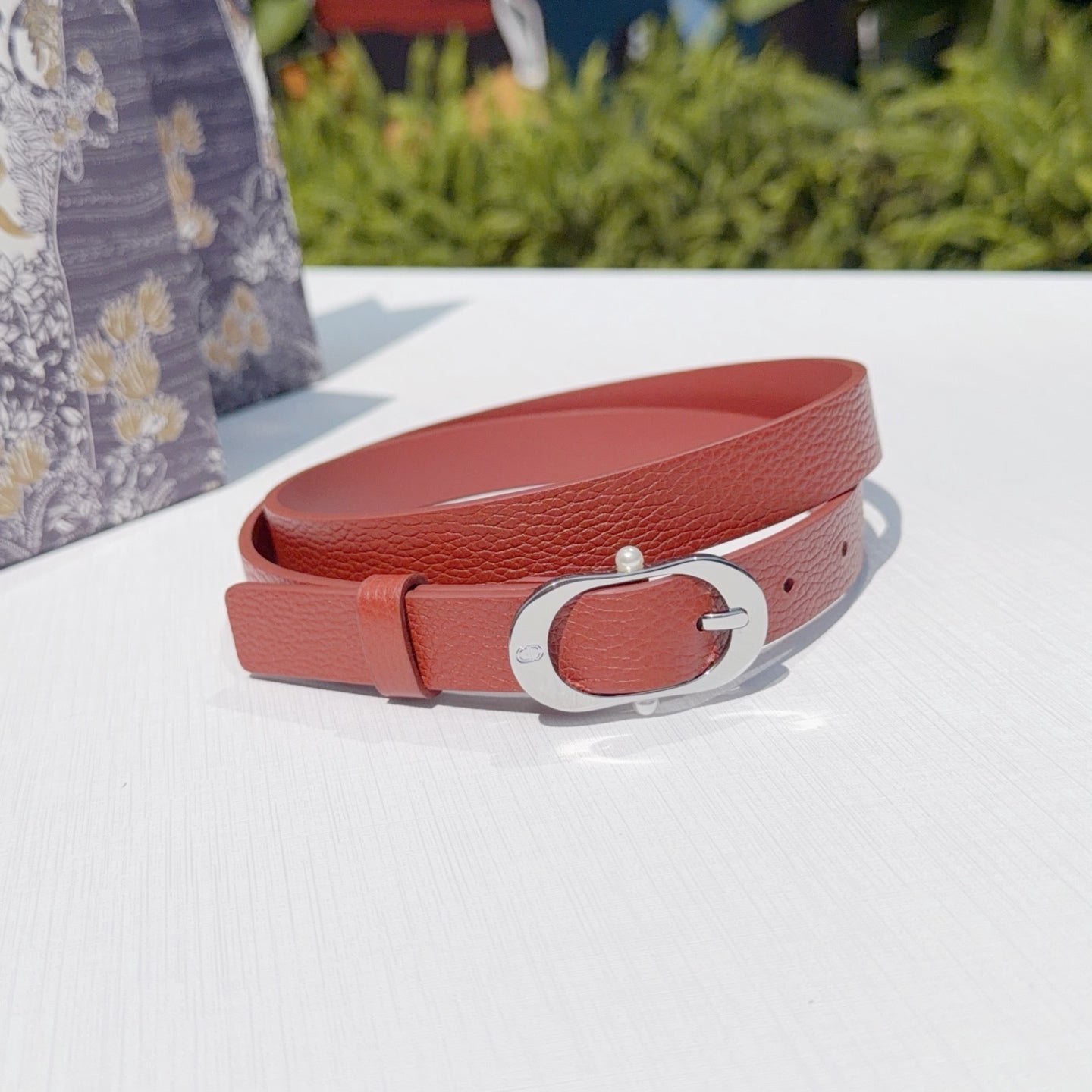 Red leather belt with silver buckle and punched size holes