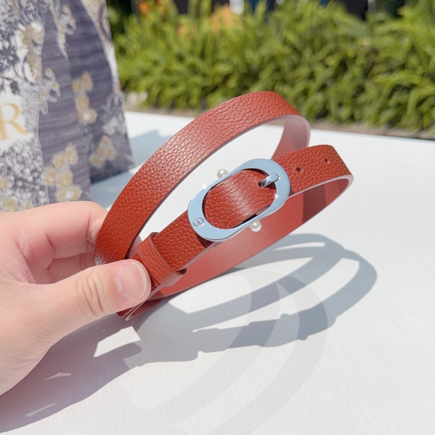 Red leather belt with silver oval buckle and metal prong