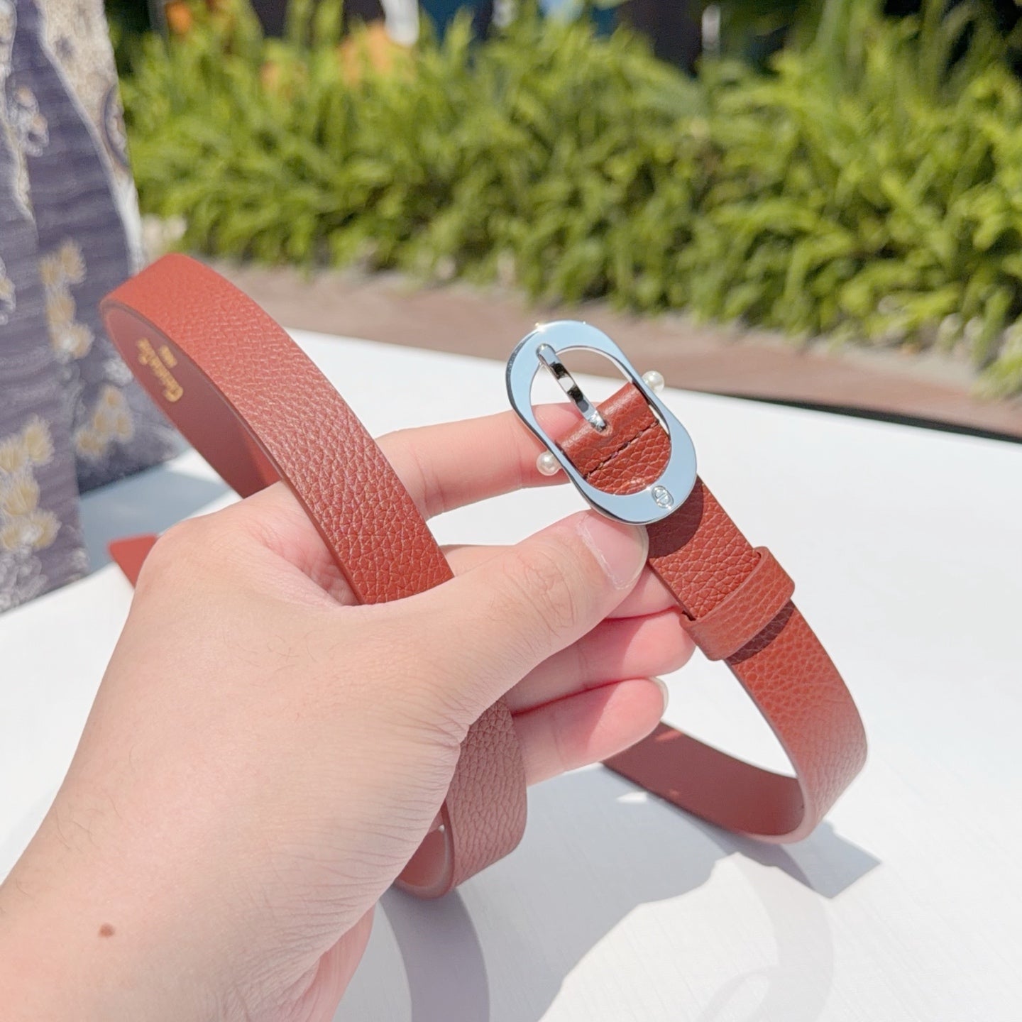 Red leather belt with silver buckle clasp held in hand