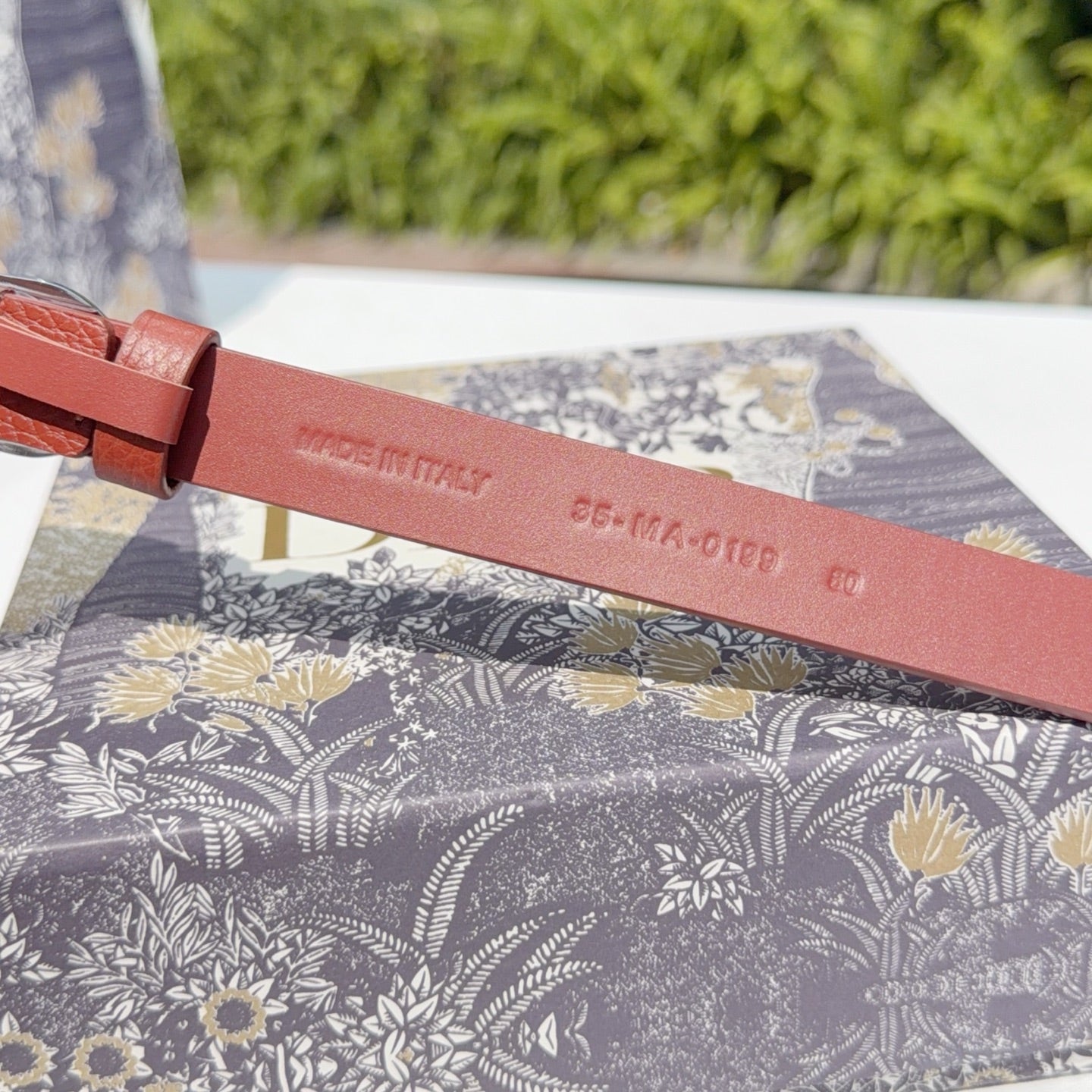 Red leather belt strap with engraved maker mark and size text