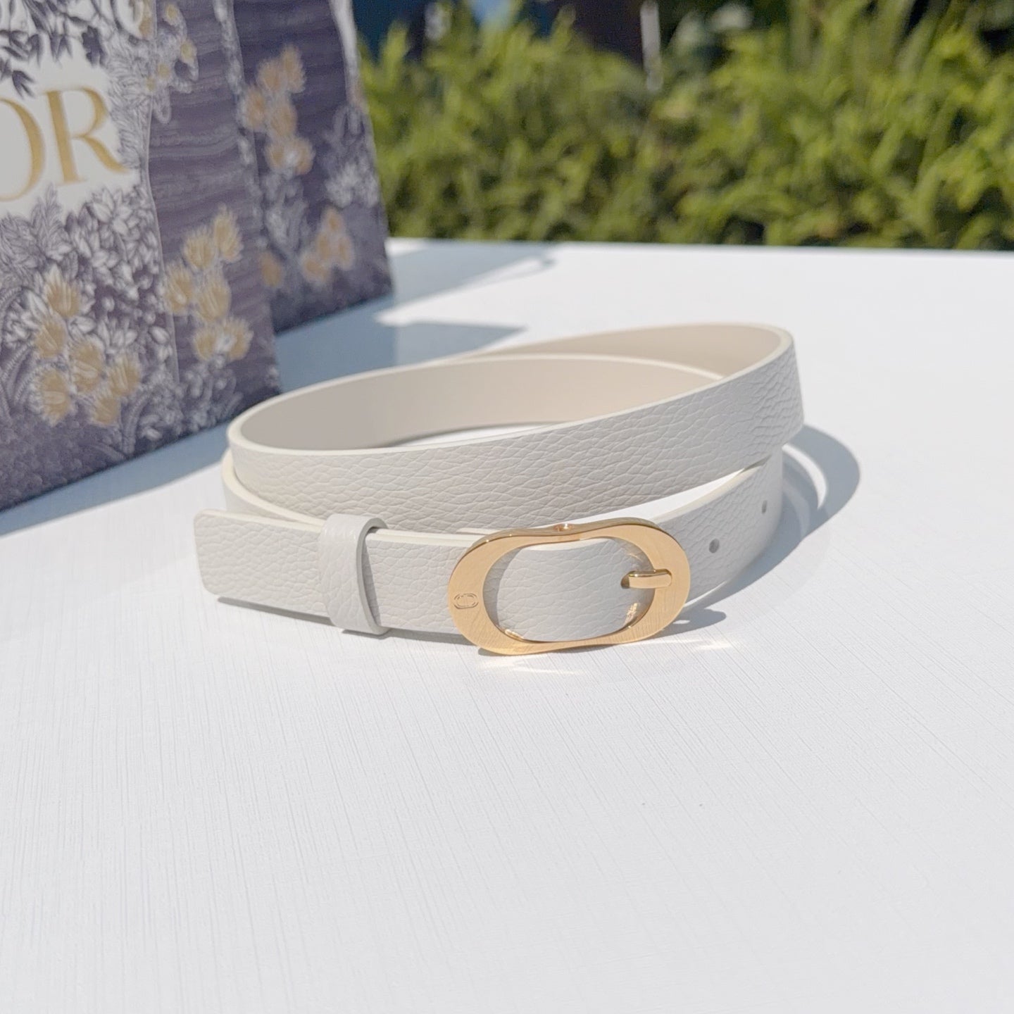 Light gray leather belt with gold-tone oval buckle, single strap loop