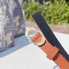 Two-tone belt with orange leather lining, dark strap, and gold buckle