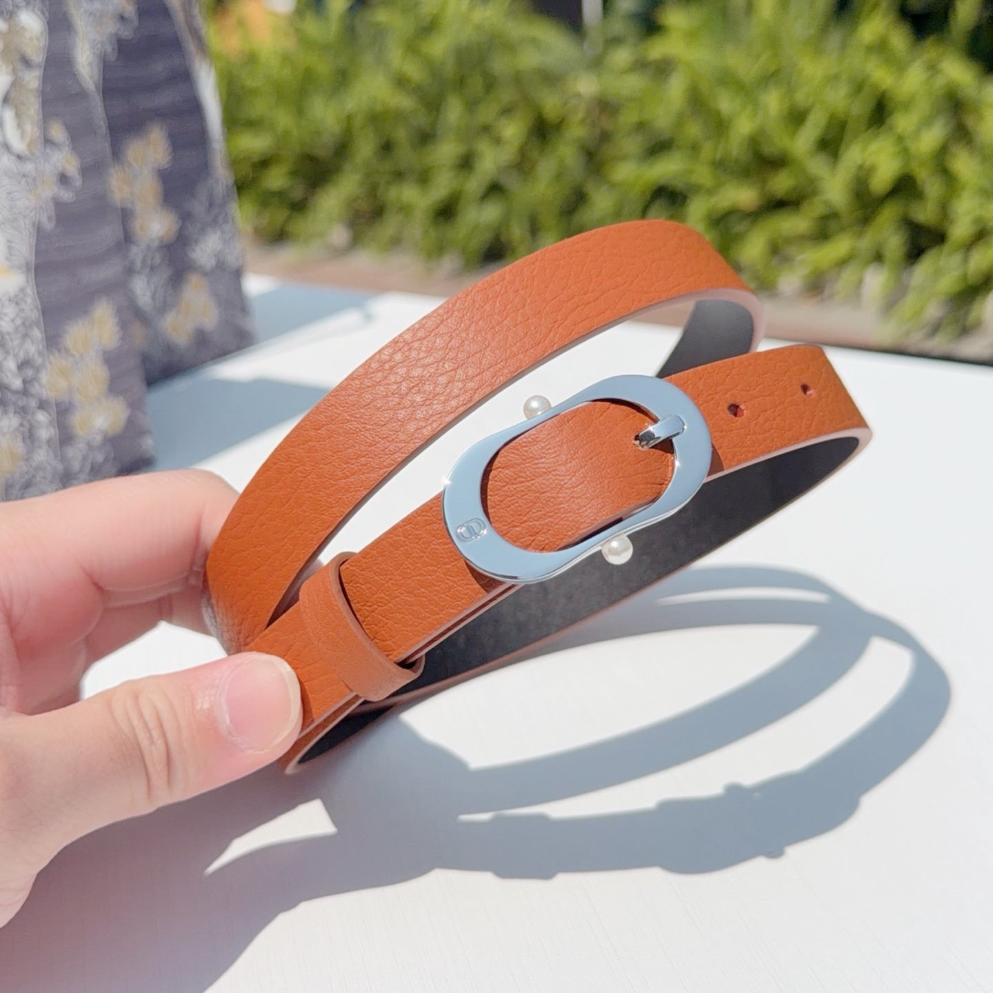 Leather belt with orange strap and silver-toned oval buckle, clasp detail