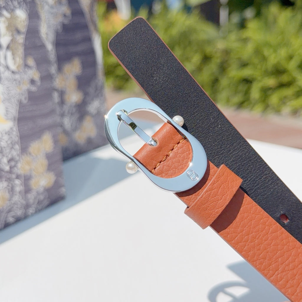 Leather belt with dark underside strap and orange top, round silver buckle