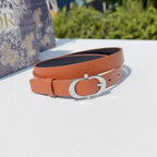Leather belt with orange strap and silver-toned oval buckle, front view