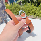 Leather belt with orange strap and silver-toned buckle, end with holes