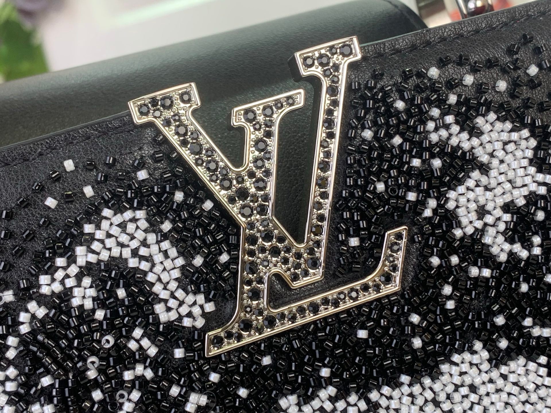 Louis Vuitton logo patch on black sequined handbag front with gold-toned trim