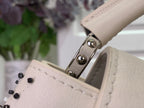 Louis Vuitton handbag strap clasp with metal hardware on light leather