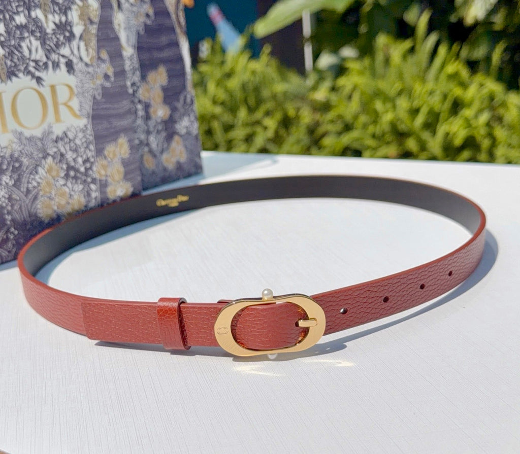 Coral leather belt with gold-tone buckle and round belt holes, lying flat